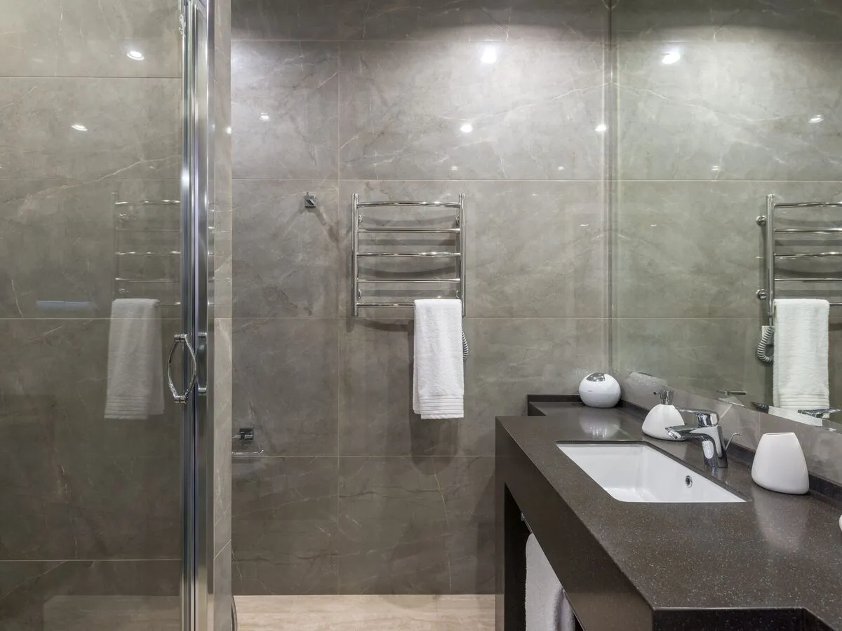 Shower room with grey stone-effect tiles, a glass door and a heated towel rail